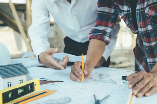 Image of engineer meeting for architectural project working with partner and engineering tools on workplace.